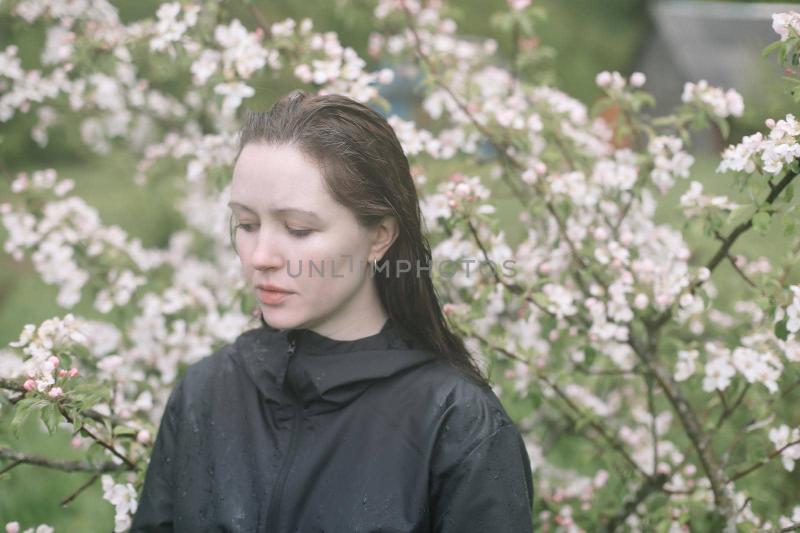 emotional portrait of a young woman standing alone under rain outdoors in spring