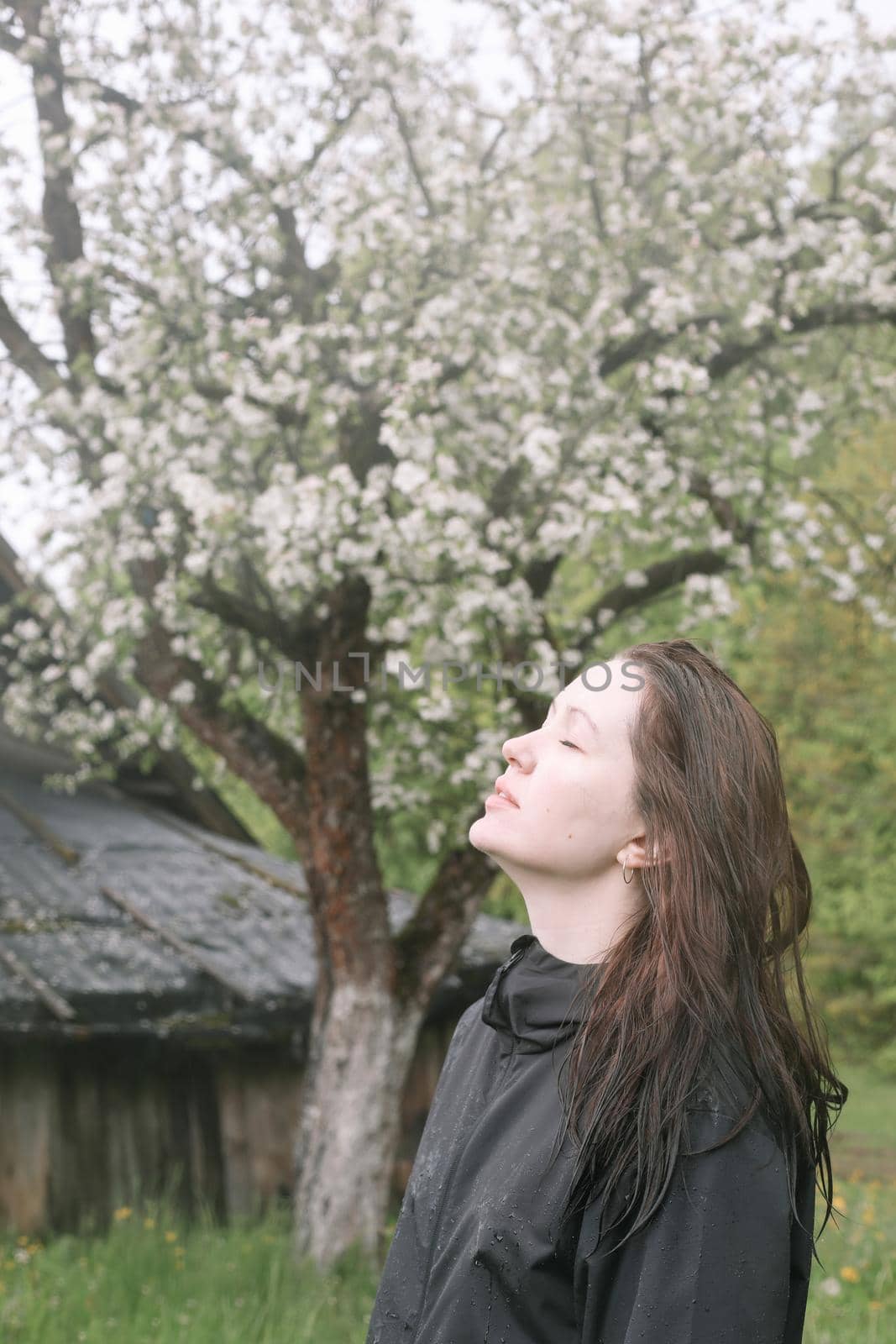 emotional portrait of a young woman standing alone under rain outdoors in spring