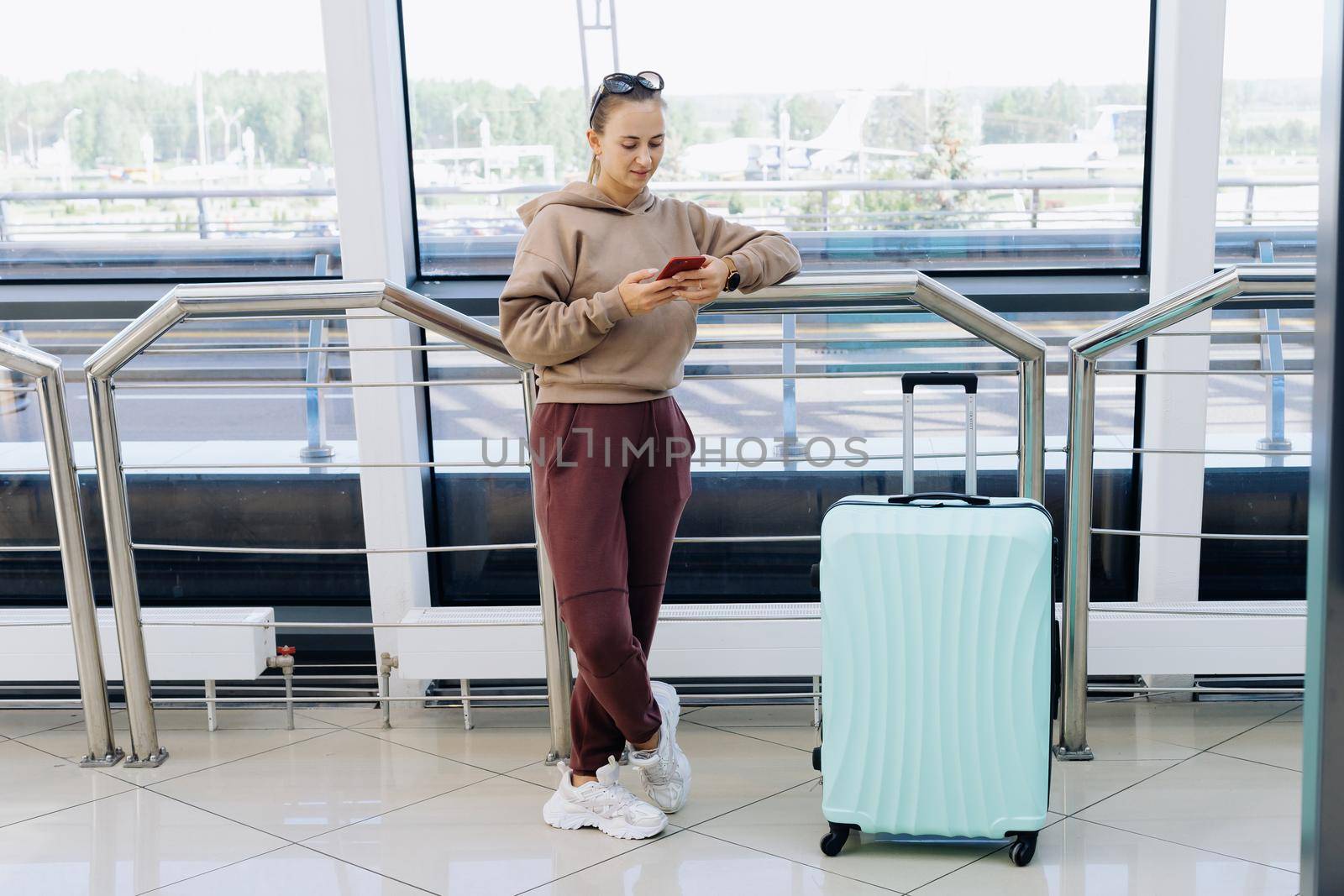 woman reading an SMS while standing at the airport . by SmartPhotoLab