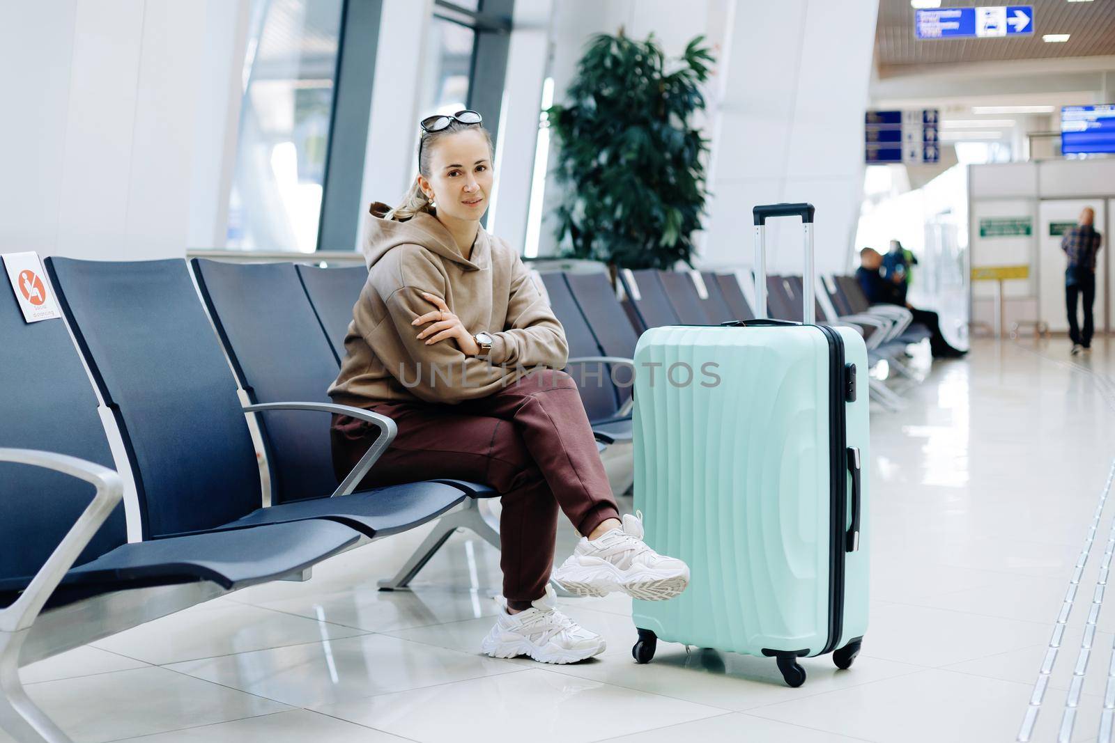 female tourist with luggage sitting in the airport waiting room .