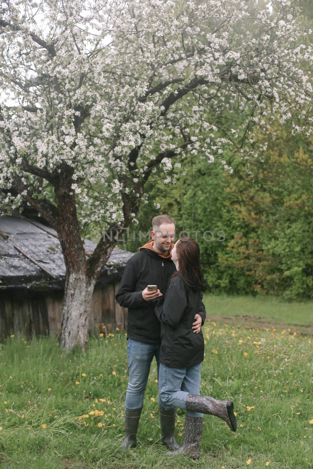 Sensual woman and man in cherry bloom. Couple in love in blossoming garden in spring. Love and romance, relationship, happy family outdoors by paralisart