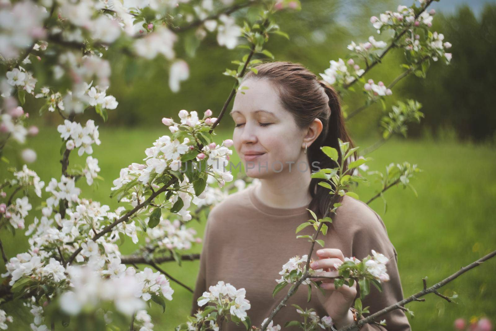 Romantic young woman in the spring garden among apple blossom