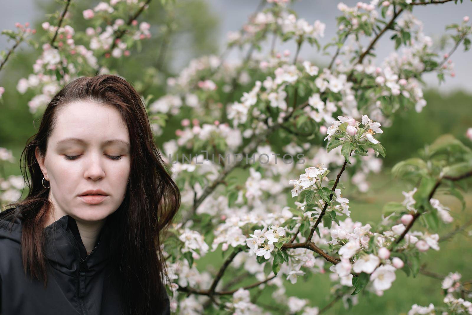 portrait of a beautiful young woman in the spring garden among apple blossom. by paralisart