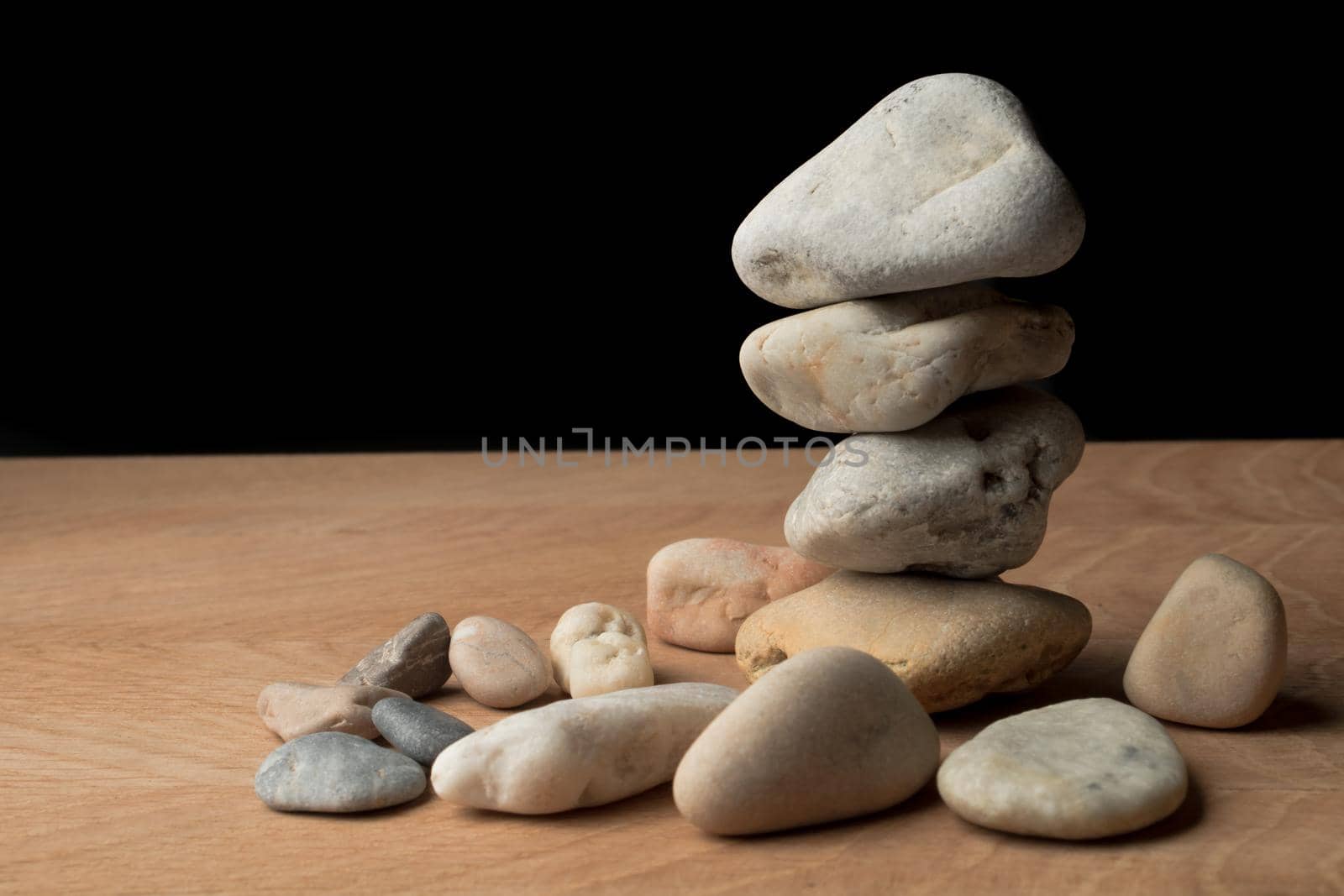 a bunch of smooth stones, on a board on a black background