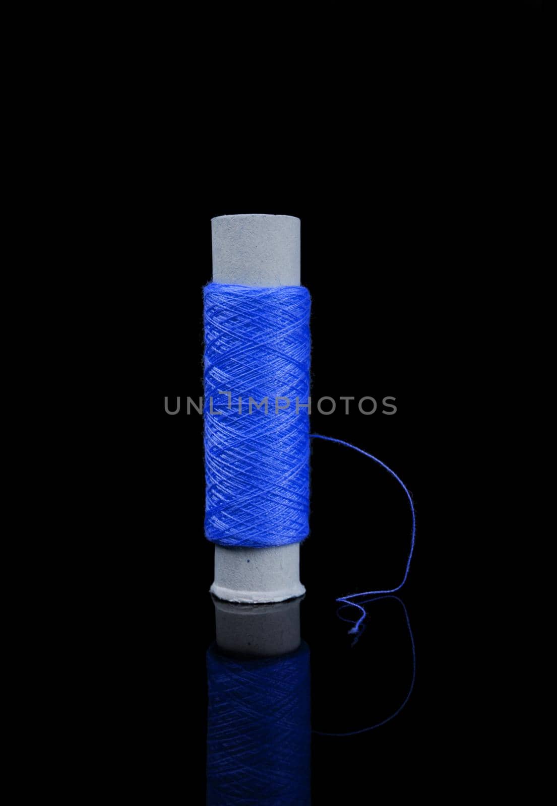 A skein of thread, a spool of thread for sewing, on a black background with reflection