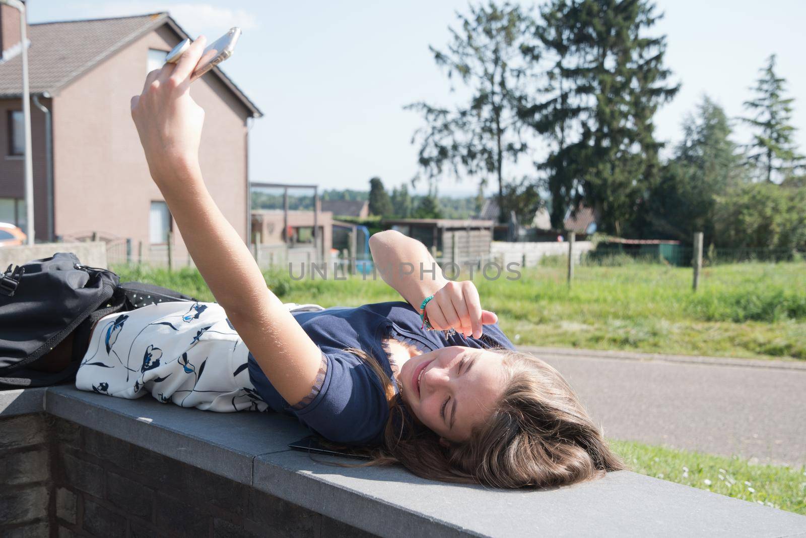 blond teenage girl takes a selfie using a mobile phone and shows a face by KaterinaDalemans