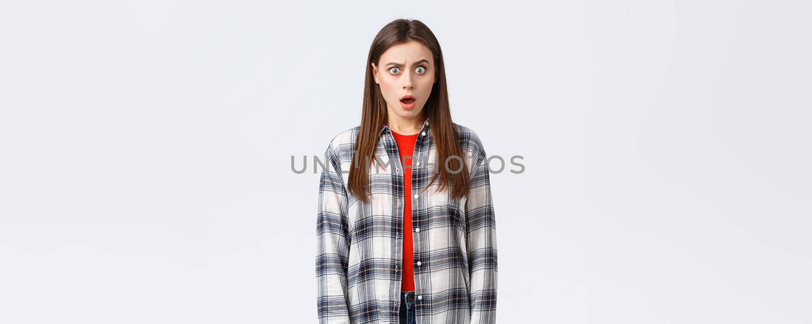 Lifestyle, different emotions, leisure activities concept. Shocked and puzzled attractive female student hear something strange, surprising news, drop jaw and staring astonished camera by Benzoix