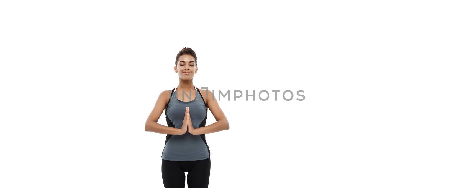 Healthy and Fitness concept - Beautiful American African lady in fitness clothing doing yoga and meditation. Isolated on white background