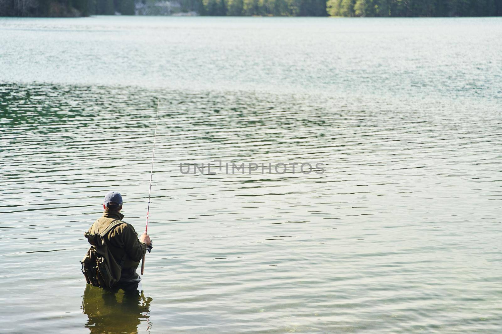 Fisher man stands in the water and catch fish in the lake on a background of mountains. High quality photo