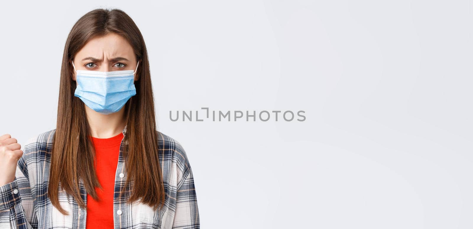 Coronavirus outbreak, leisure on quarantine, social distancing and emotions concept. Upset and disappointed young woman in medical mask frowning, condemn smth, pointing finger left displeased by Benzoix