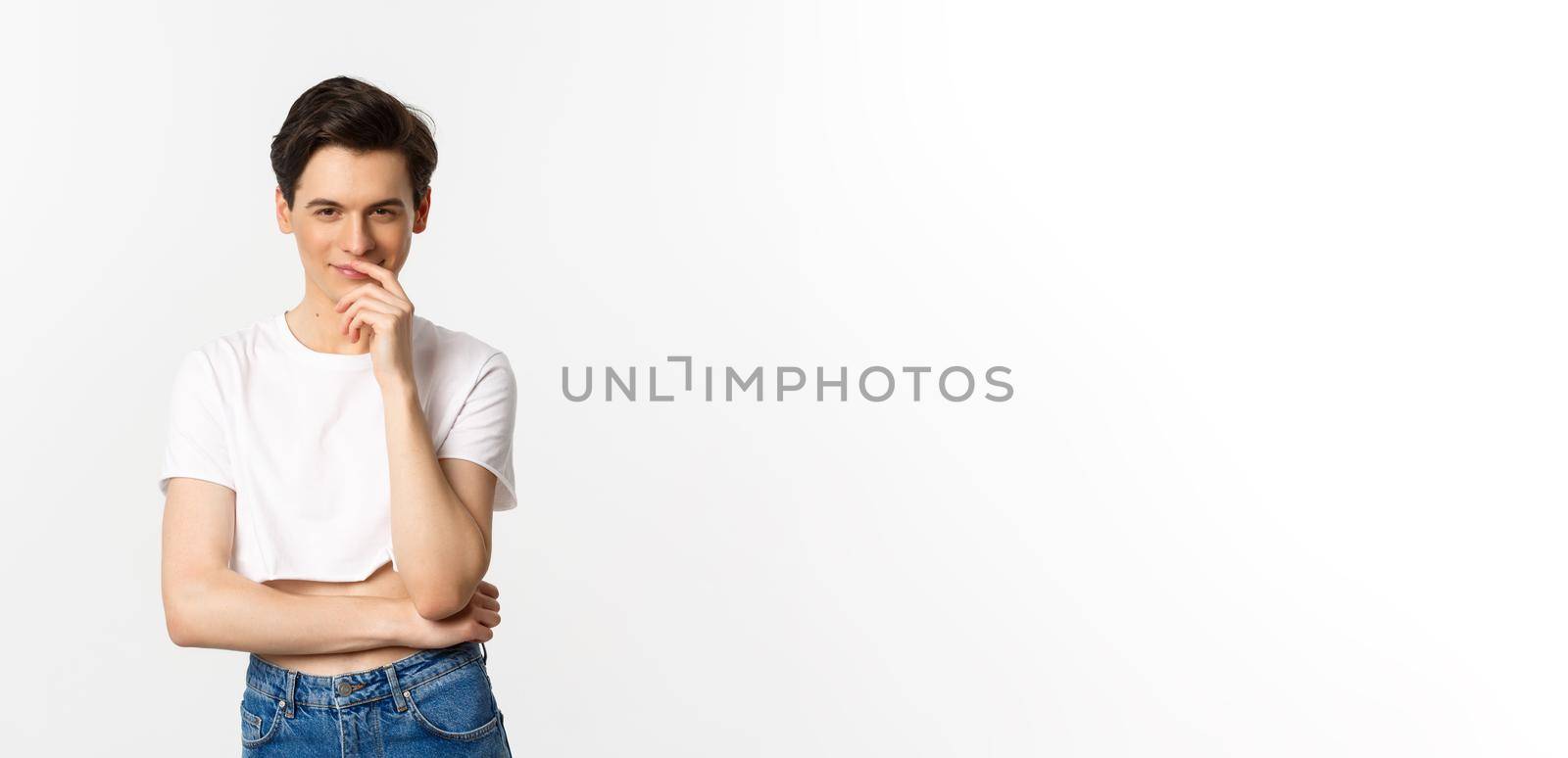 Lgbtq and pride concept. Satisfied young gay man thinking, having an idea and smiling while staring at camera, wearing crop top, white background by Benzoix