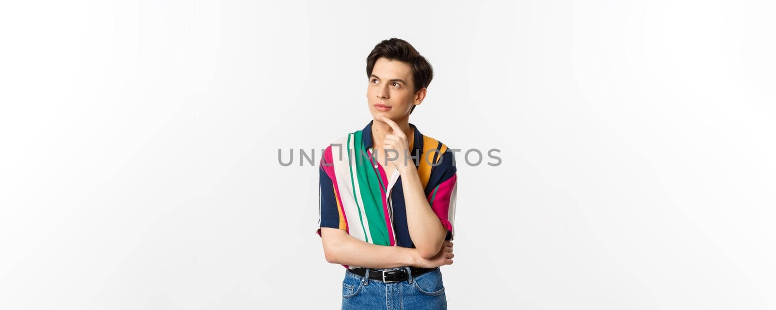 Portrait of thoughtful queer man in stylish shirt, looking at upper left corner and thinking, making choice, standing over white background by Benzoix
