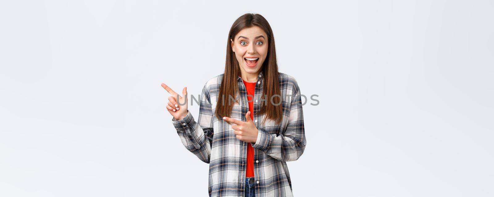 Lifestyle, different emotions, leisure activities concept. Excited female customer hear special discounts pointing shop promo. Astonished woman smiling happy and showing way, indicate left banner.
