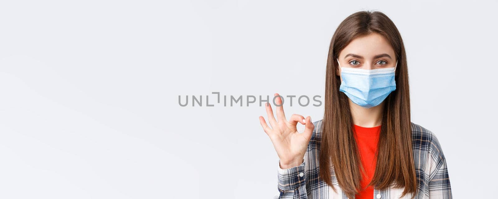 Coronavirus outbreak, leisure on quarantine, social distancing and emotions concept. Close-up of satisfied good-looking woman in medical mask, assure all good, show okay guarantee gesture.