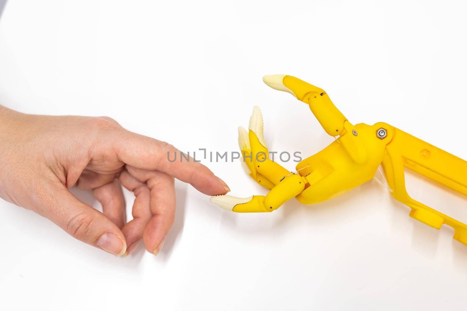 Woman's hand and a plastic hand prosthesis for a child on a white background