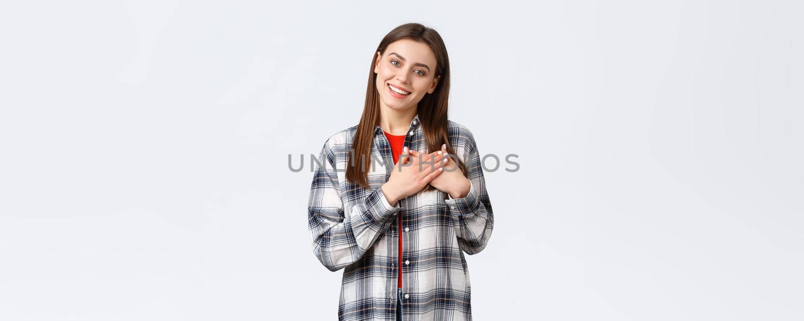 Lifestyle, different emotions, leisure activities concept. Touched tender young woman in checked shirt, hold hands on heart, being flattered, keep warm and tender memories in soul, smiling pleased by Benzoix