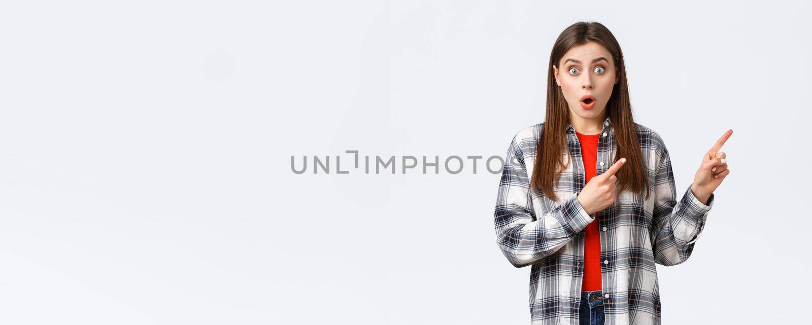 Lifestyle, different emotions, leisure activities concept. Wow amazing look here. Astonished young speechless girl showing cool new promo, pointing fingers upper right corner and stare camera by Benzoix