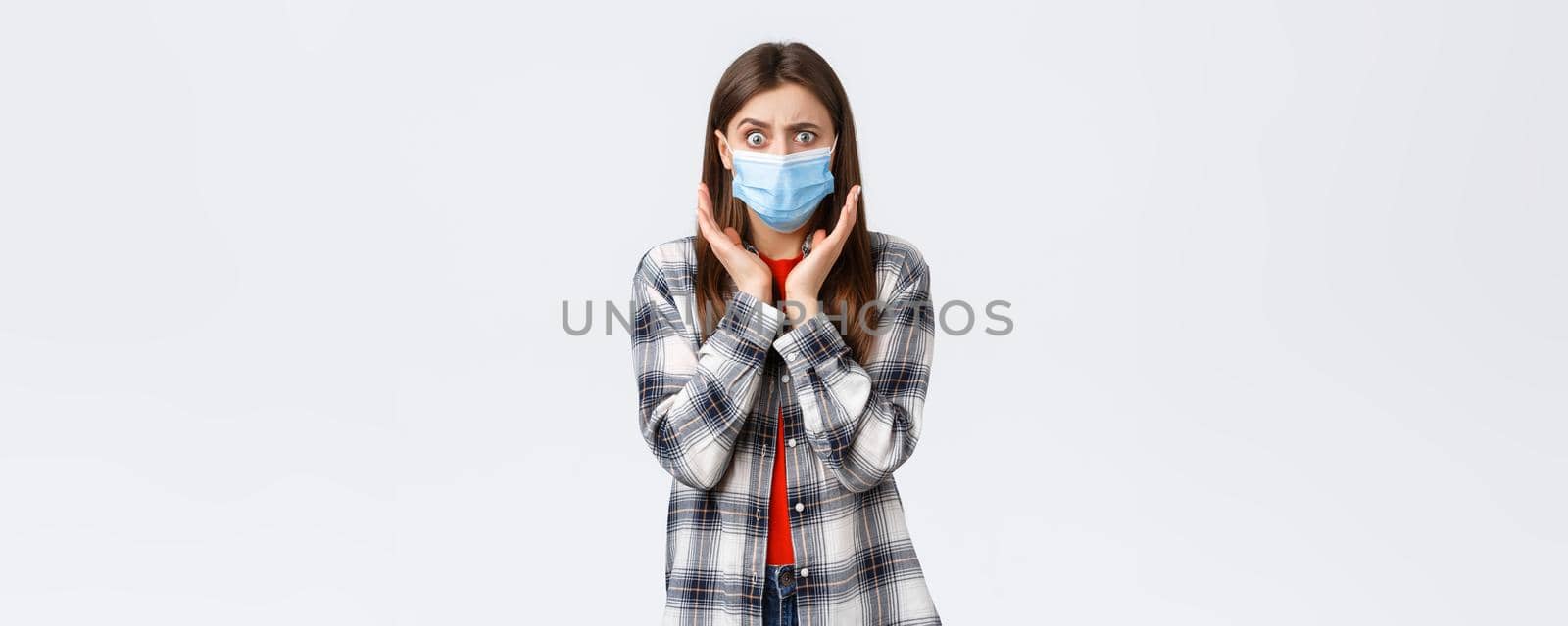 Coronavirus outbreak, leisure on quarantine, social distancing and emotions concept. Concerned and shocked young woman hear bad news. Girl in medical mask gasping and looking worried camera.