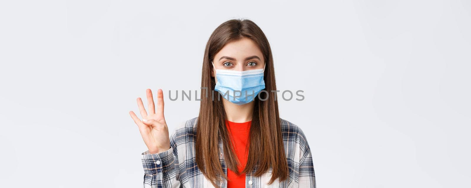 Coronavirus outbreak, leisure on quarantine, social distancing and emotions concept. Cheerful attractive woman in medical mask showing number four, make order, white background.