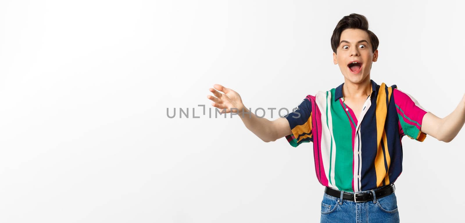 Amazed funny guy spread hands sideways and screaming of excitement, reaching for what he wants, standing over white background.
