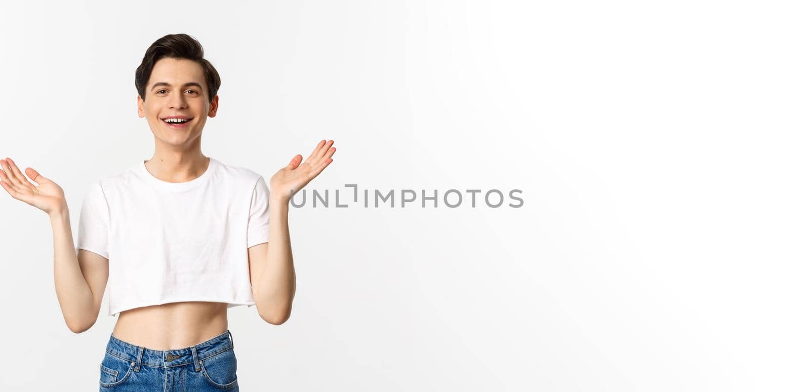 Lgbtq and pride concept. Happy and satisfied young gay man in crop top clapping hands proud, smiling at camera, standing over white background.