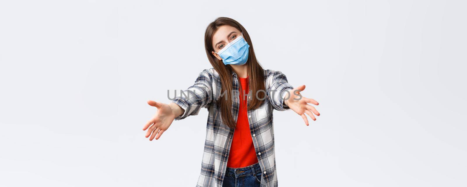 Coronavirus outbreak, leisure on quarantine, social distancing and emotions concept. Friendly-looking young supportive girl in medical mask reaching hands to give hug or hold something by Benzoix