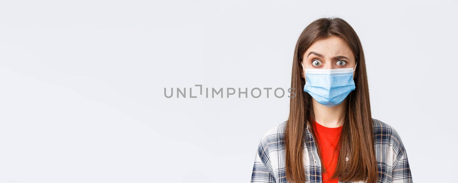 Coronavirus outbreak, leisure on quarantine, social distancing and emotions concept. Confused and startled girl in medical mask seeing something strange, raise eyebrow skeptical.