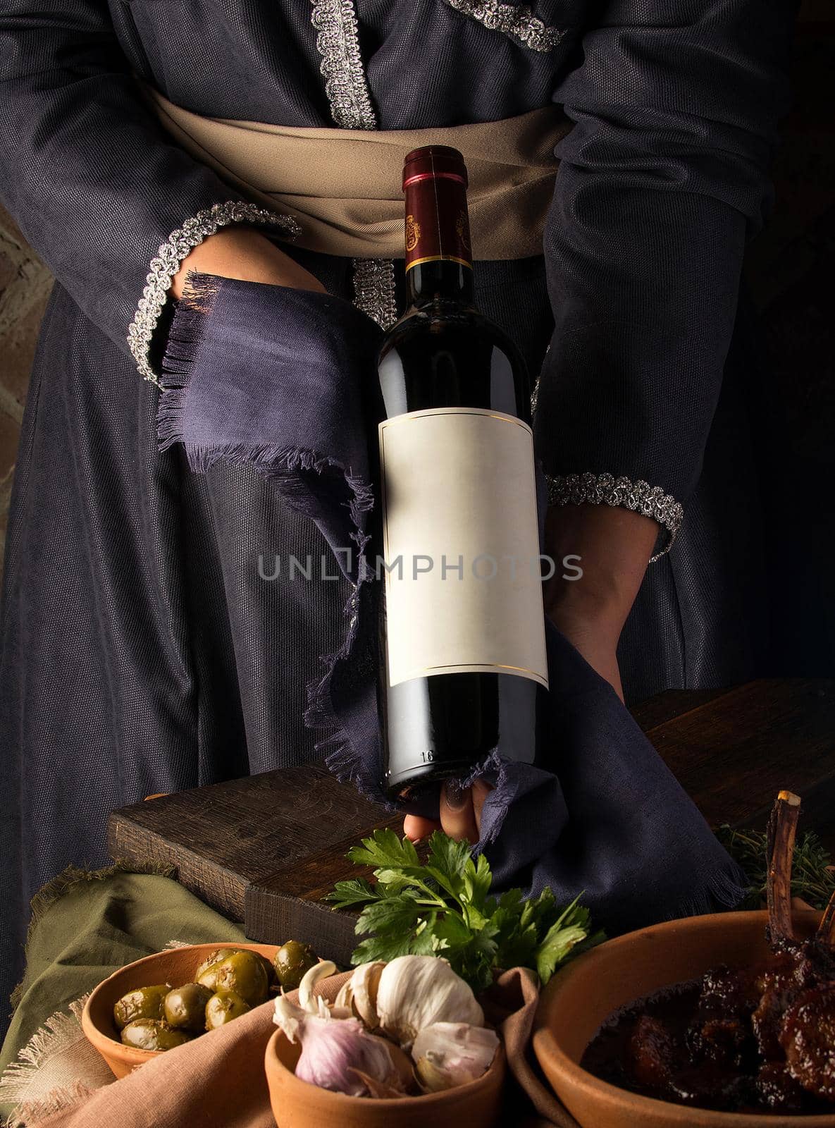 Vertical shot of a person in a traditional costume showing a wine bottle by A_Karim