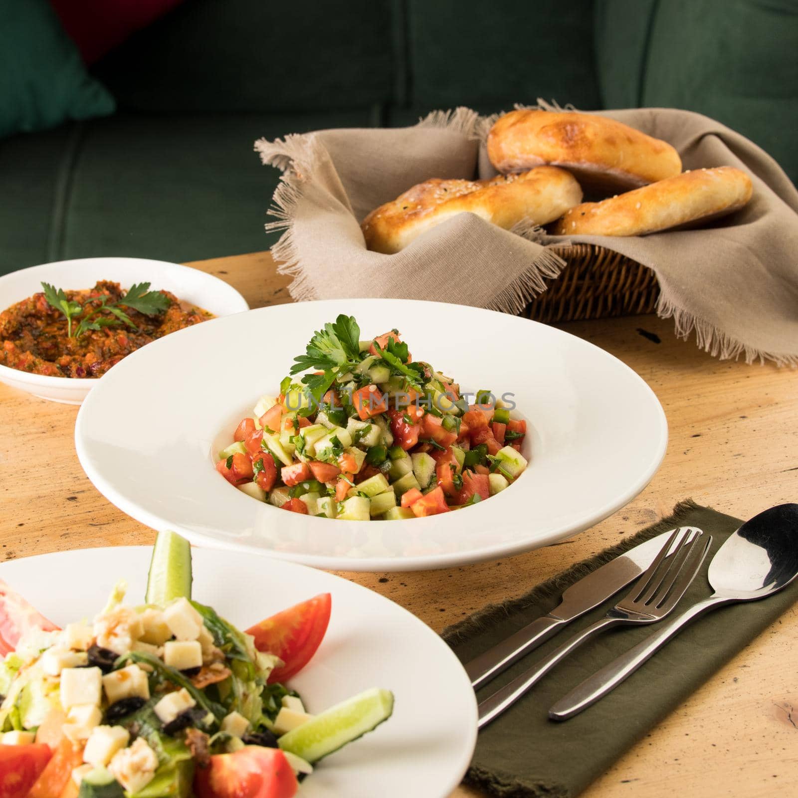 A close up shot of salads and appetizers near basket of breads