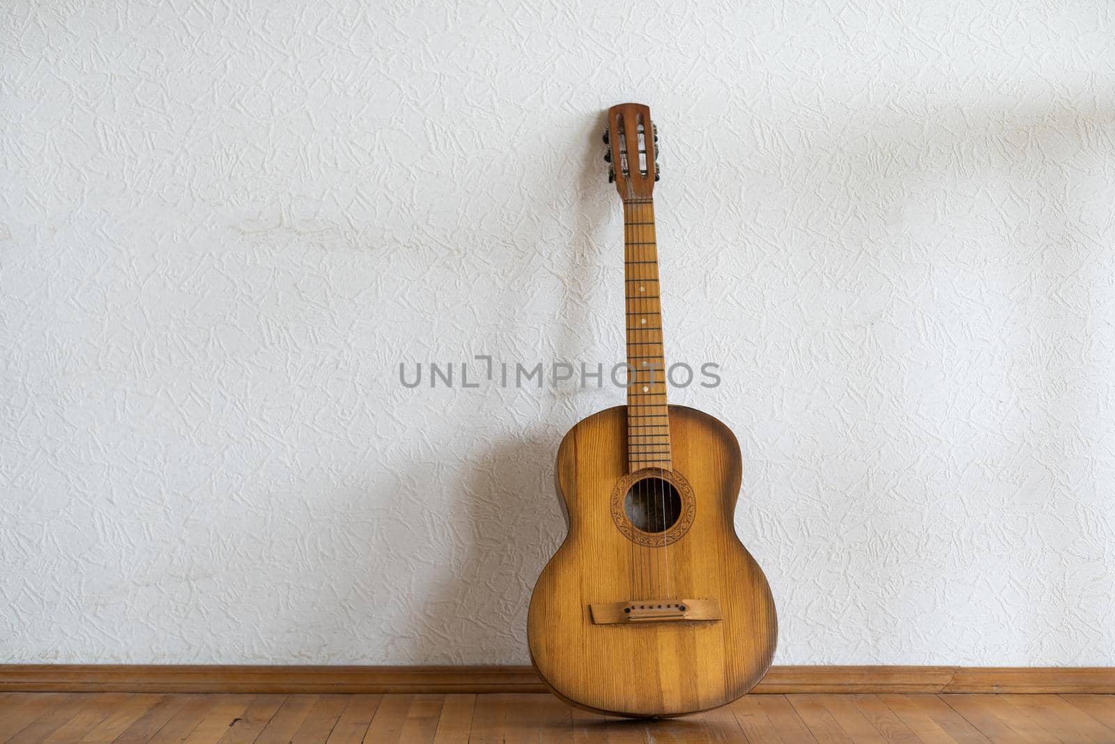 classic guitar lying in front of a wall as background by Andelov13