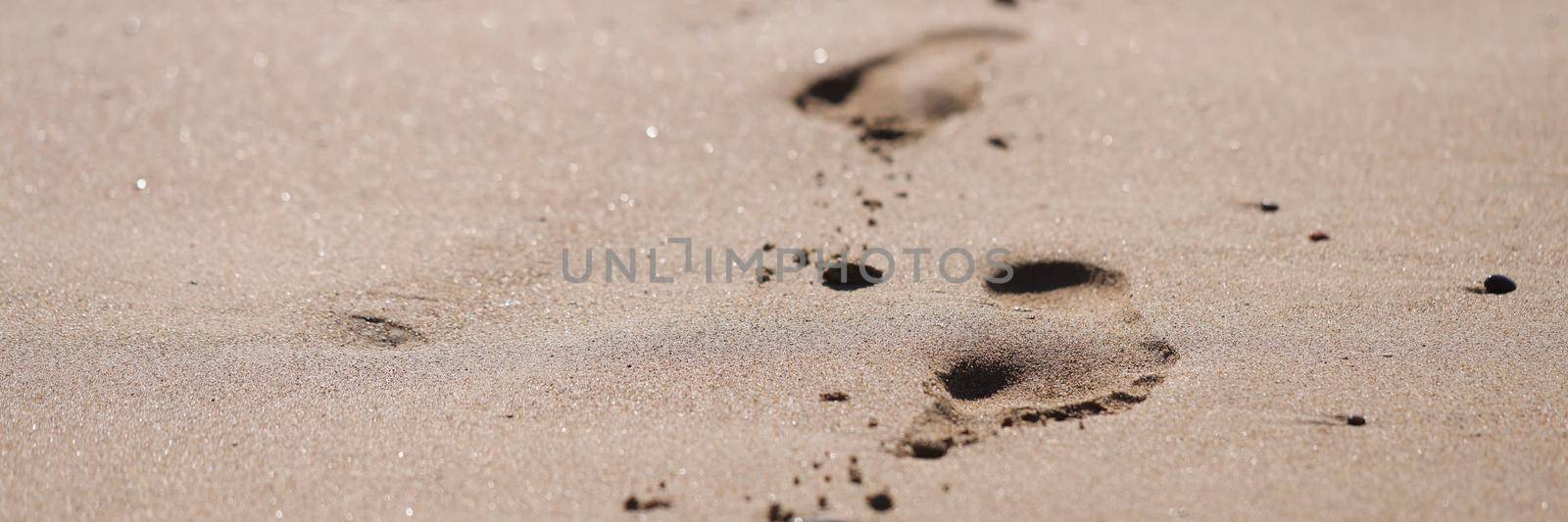 Human foot prints on golden beach sand by kuprevich