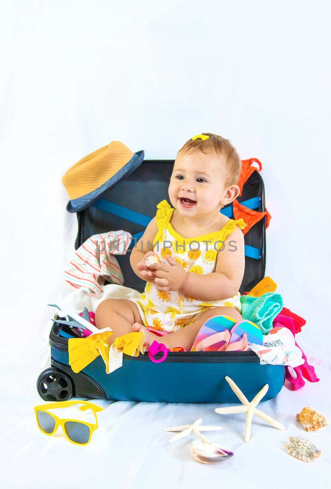 Baby is sitting in a suitcase, getting ready for a travel. Selective focus. Child.