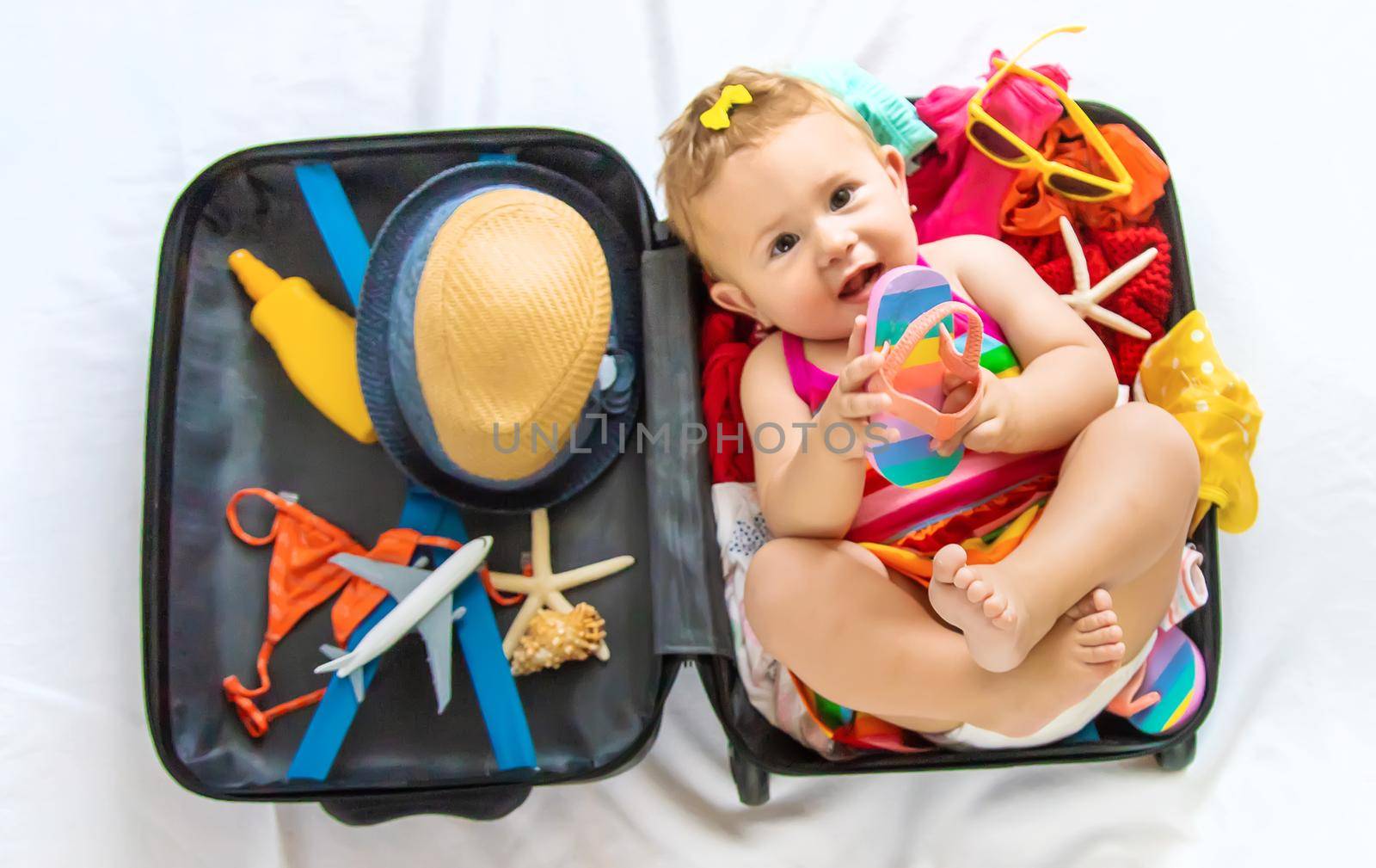 Baby is sitting in a suitcase, getting ready for a travel. Selective focus. Child.