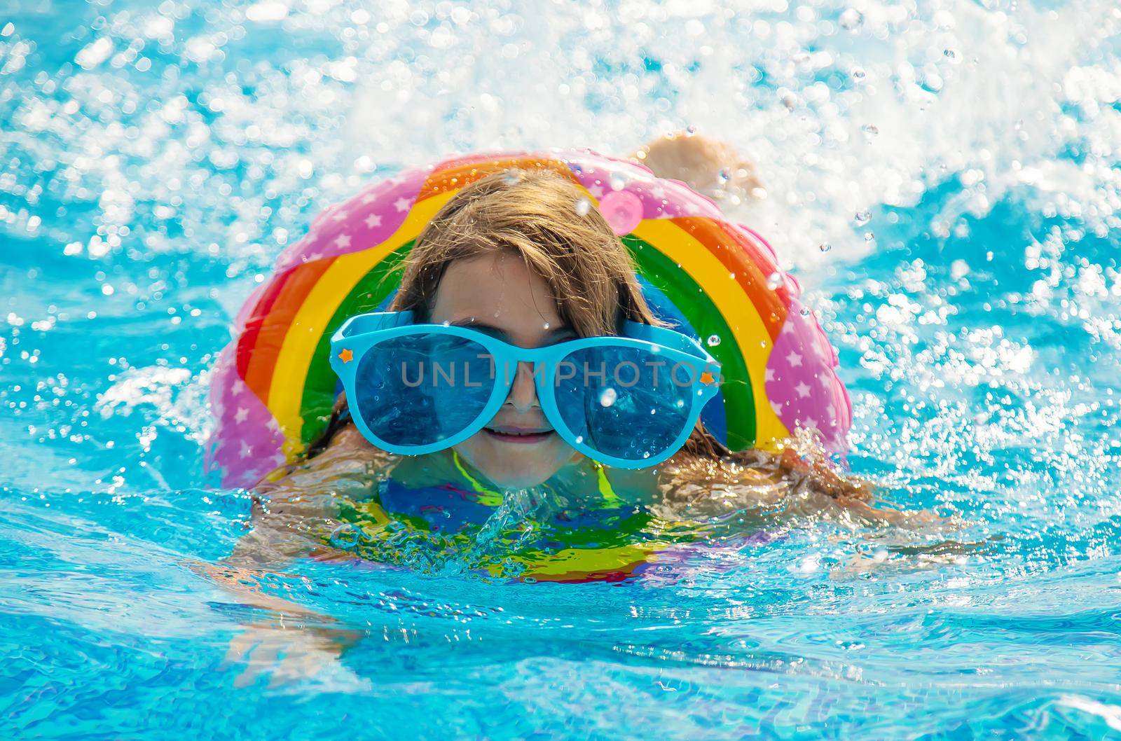 The child is swimming in the pool. Selective focus. Kid.