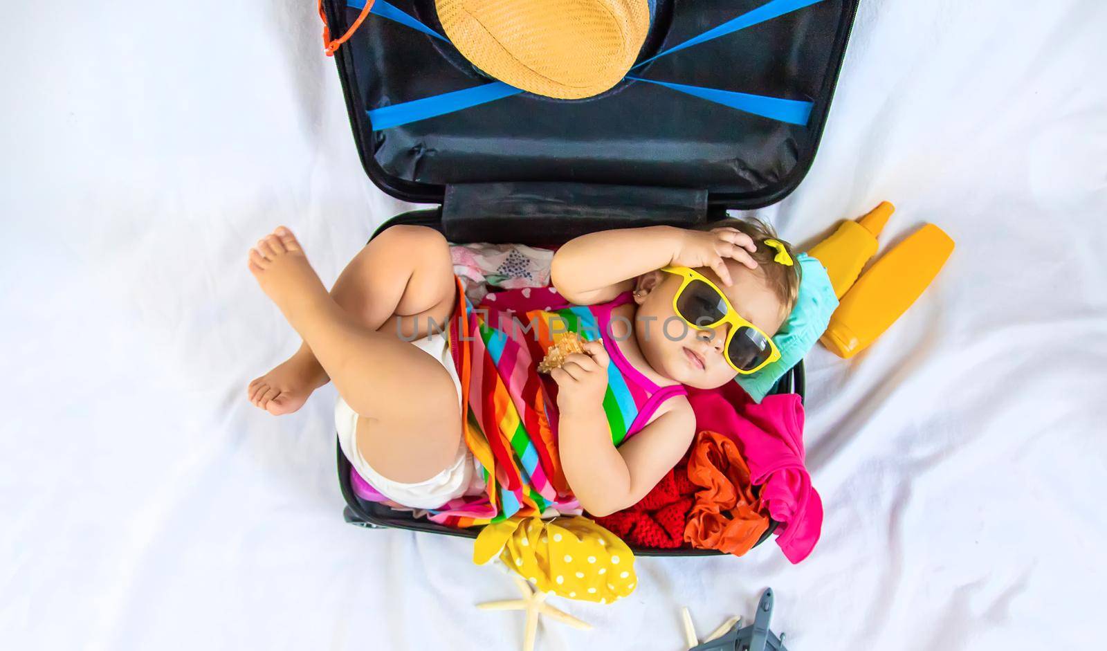 Baby is sitting in a suitcase, getting ready for a travel. Selective focus. Child.