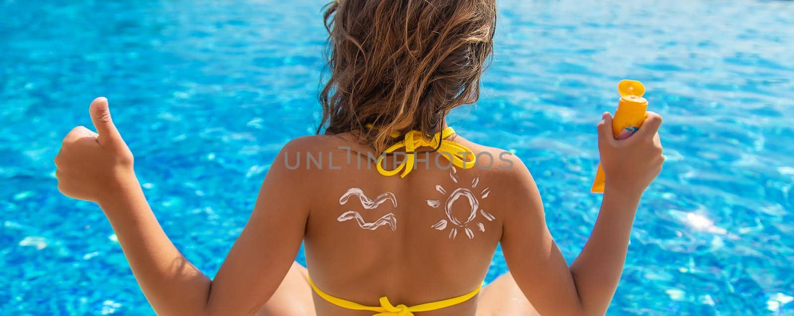 The child puts sunscreen on his back. Selective focus. Kid.