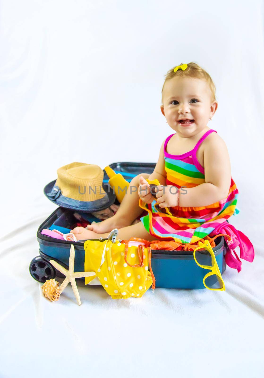 Baby is sitting in a suitcase, getting ready for a travel. Selective focus. Child.