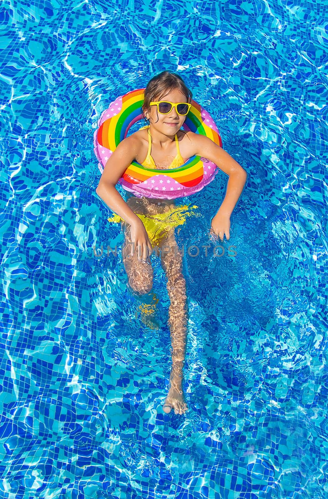 The child swims with a circle in the pool. Selective focus. Kid.