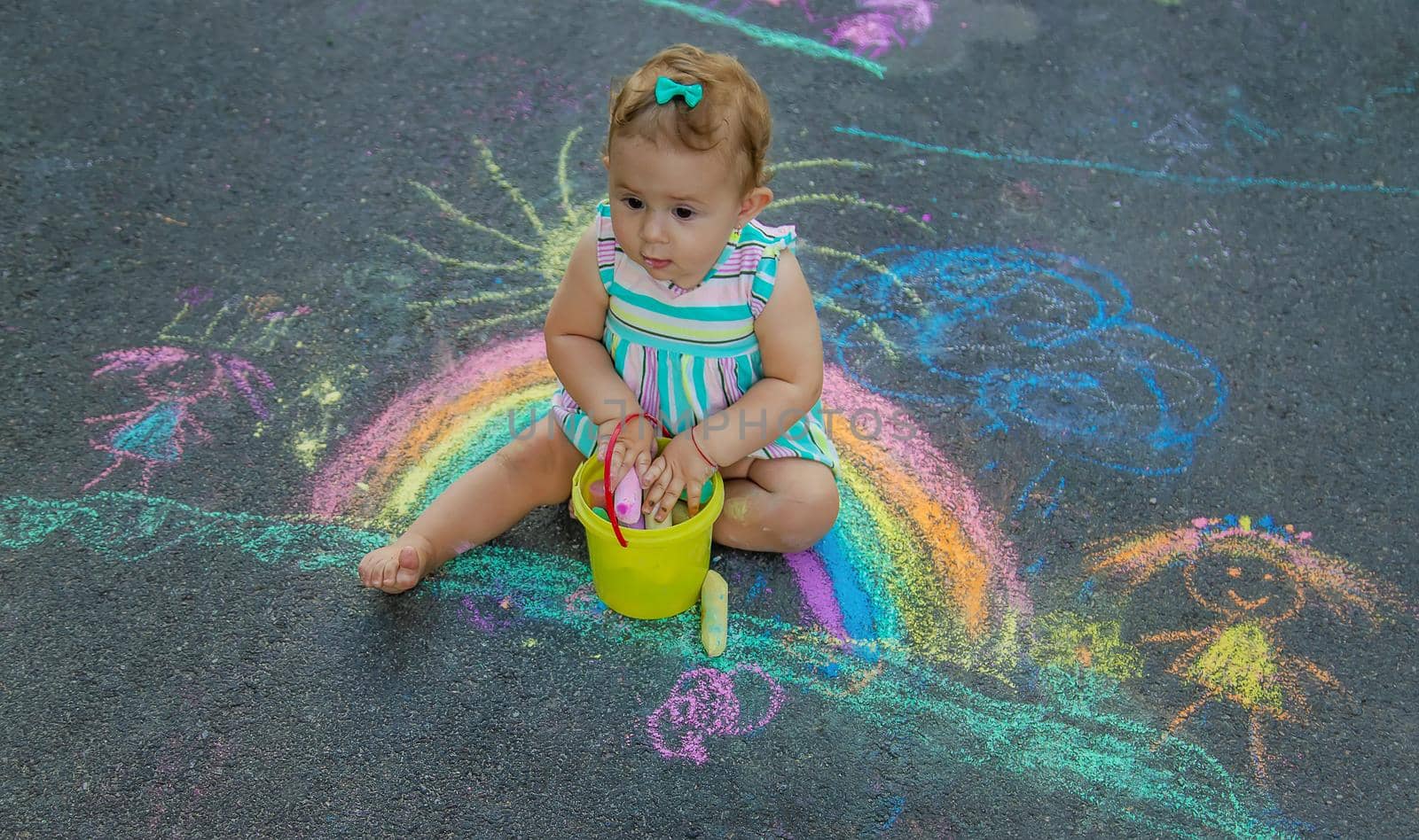Baby draws a rainbow on the pavement with chalk. Selective focus. Nature.