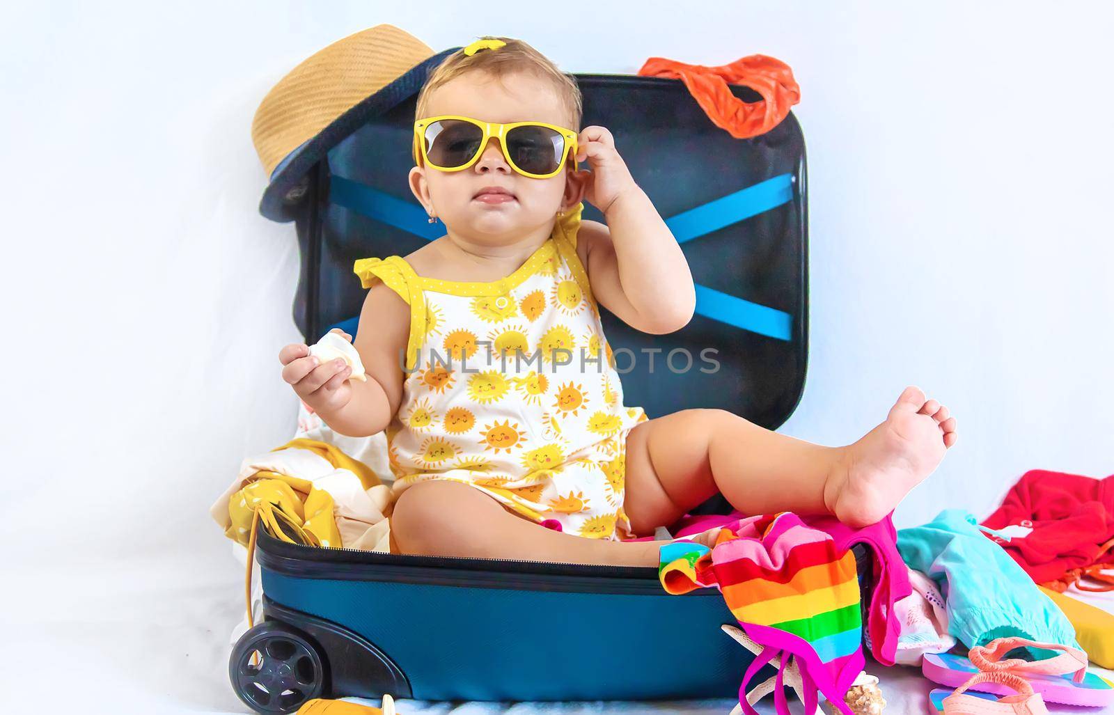 Baby is sitting in a suitcase, getting ready for a travel. Selective focus. Child.