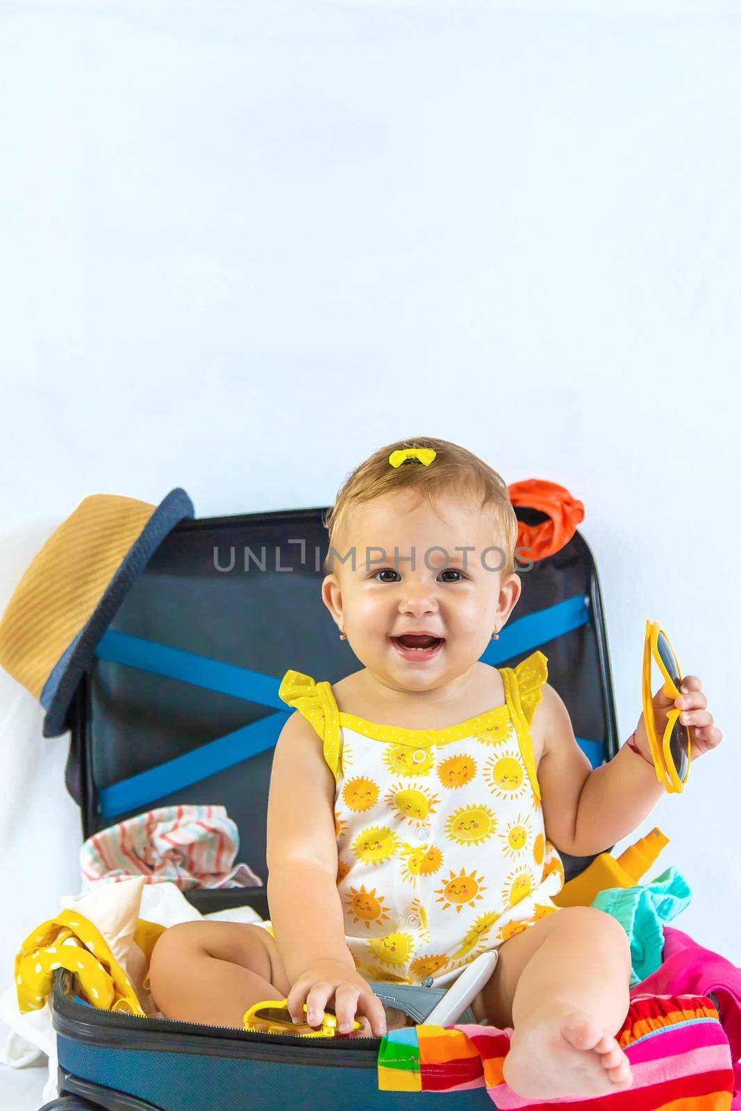 Baby is sitting in a suitcase, getting ready for a travel. Selective focus. Child.