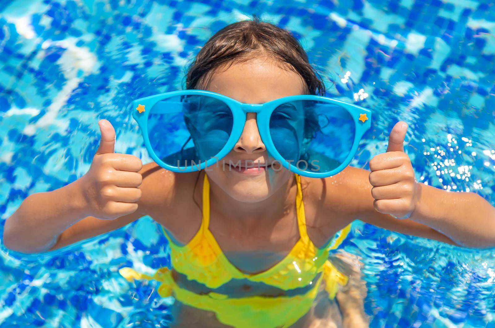 The child is swimming in the pool. Selective focus. Kid.