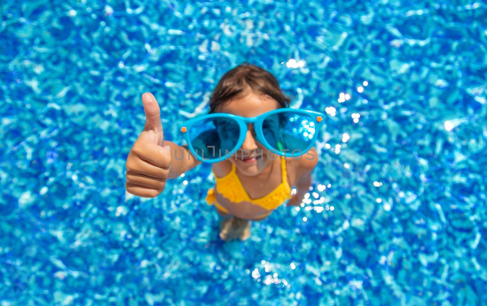 The child is swimming in the pool. Selective focus. Kid.