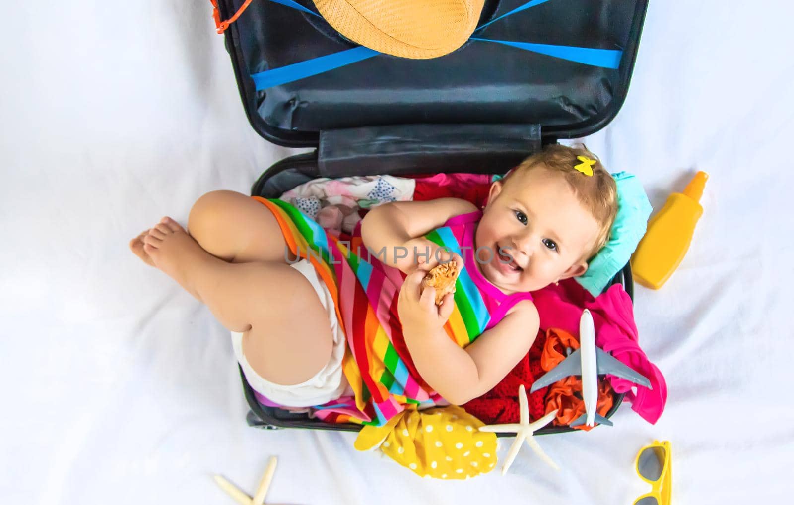 Baby is sitting in a suitcase, getting ready for a travel. Selective focus. Child.