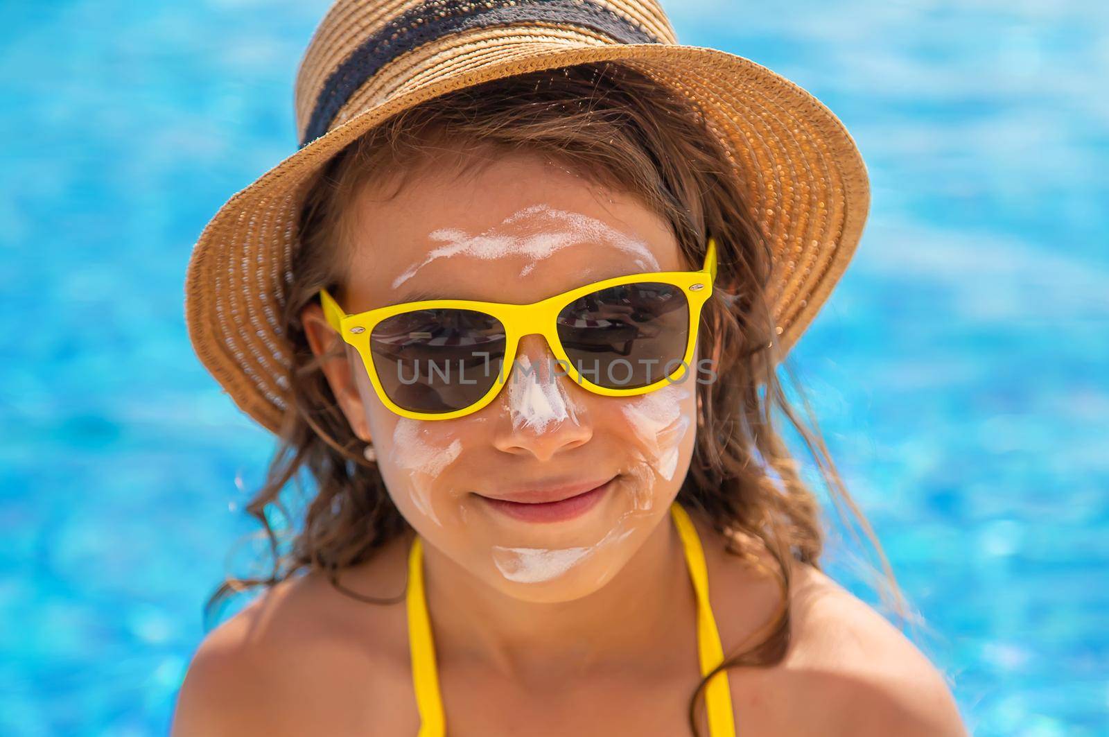 The child is putting sunscreen on her face. Selective focus. Kid.