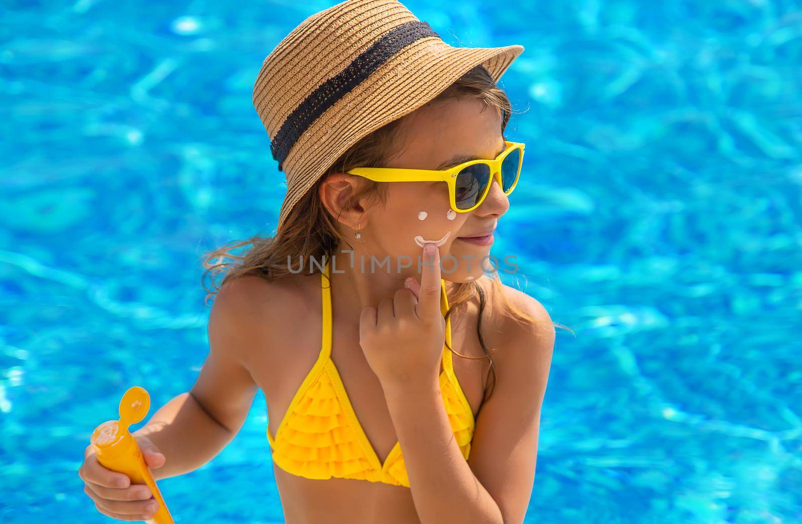 The child is putting sunscreen on her face. Selective focus. Kid.