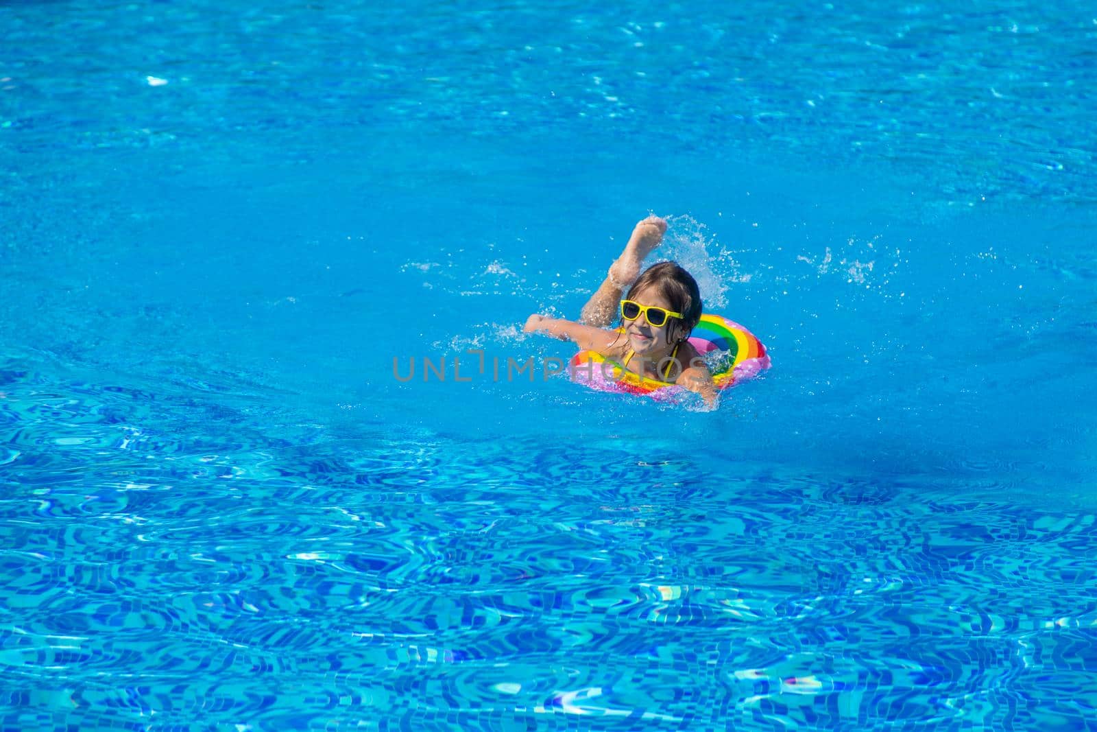 The child swims with a circle in the pool. Selective focus. Kid.