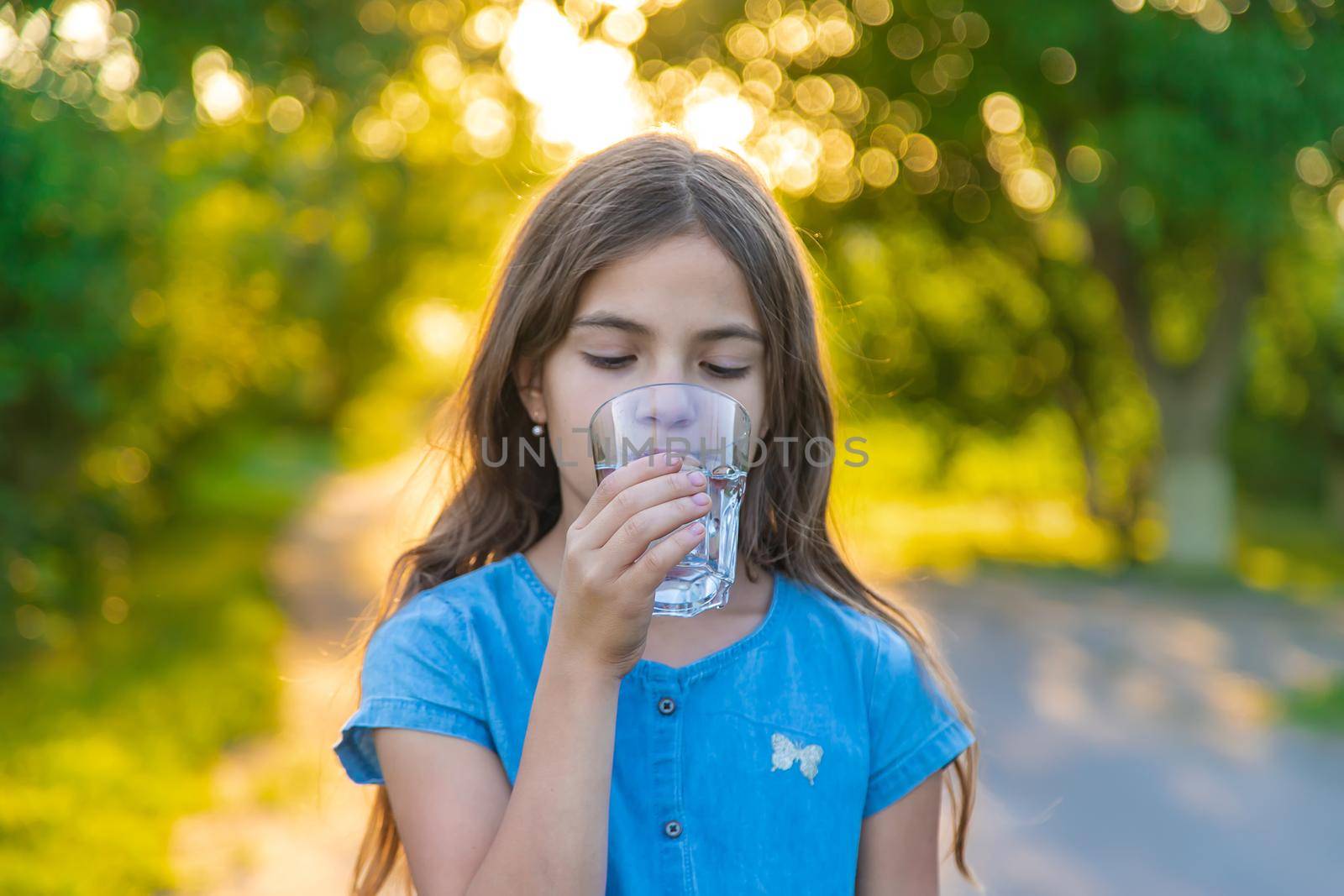 The child drinks water from a glass. Selective focus. by yanadjana