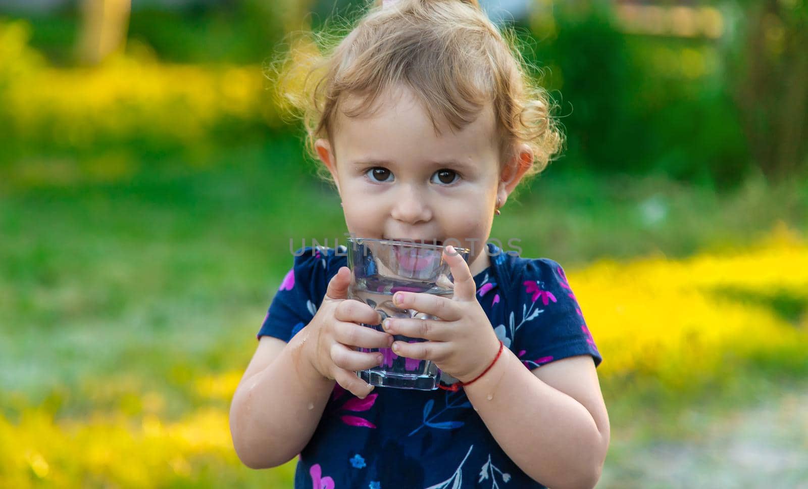 The child drinks water from a glass. Selective focus. by yanadjana