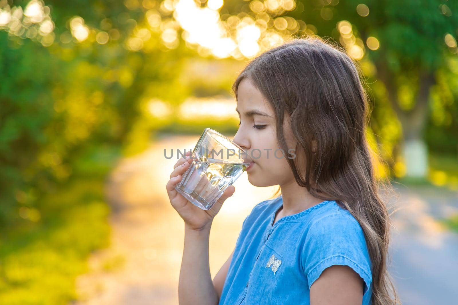 The child drinks water from a glass. Selective focus. Kid.